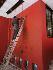 pintura-exterior-pared-roja-escalera-trabajador-pintando-casa-servicio-contratista